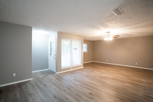 unfurnished room with ceiling fan, wood-type flooring, and a textured ceiling