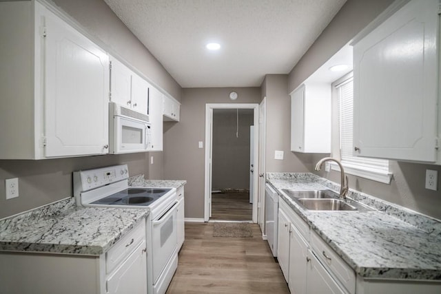 kitchen featuring sink, white appliances, white cabinetry, light stone countertops, and light hardwood / wood-style floors