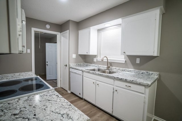 kitchen with white dishwasher, sink, white cabinetry, and light hardwood / wood-style flooring