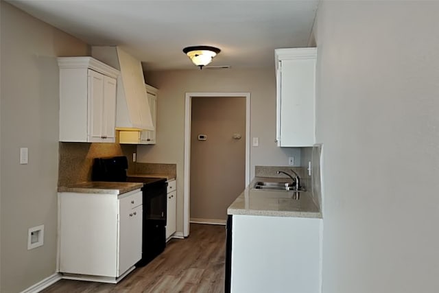 kitchen with sink, electric range, tasteful backsplash, wood-type flooring, and white cabinets