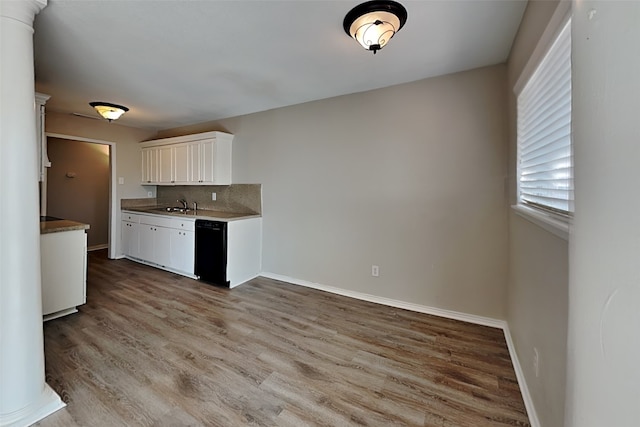 kitchen with tasteful backsplash, black dishwasher, sink, white cabinets, and light hardwood / wood-style floors