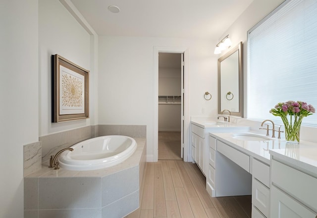 bathroom featuring tiled tub, vanity, and hardwood / wood-style floors