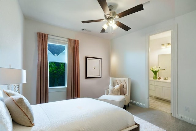 bedroom with connected bathroom, light colored carpet, and ceiling fan