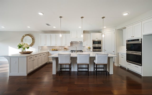 kitchen with appliances with stainless steel finishes, pendant lighting, and white cabinets