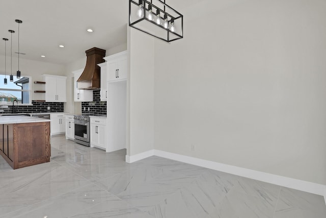 kitchen featuring white cabinetry, decorative light fixtures, custom exhaust hood, and appliances with stainless steel finishes