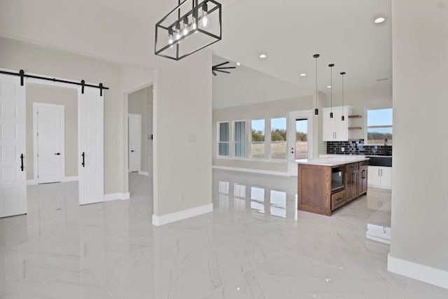 kitchen with decorative light fixtures, a center island, ceiling fan, a barn door, and white cabinets