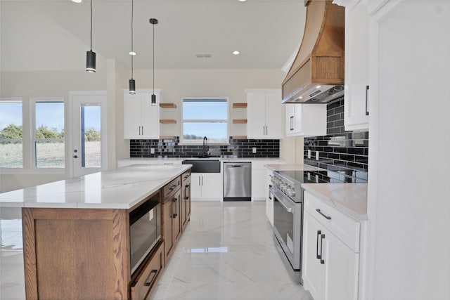 kitchen featuring a kitchen island, appliances with stainless steel finishes, white cabinetry, sink, and light stone countertops