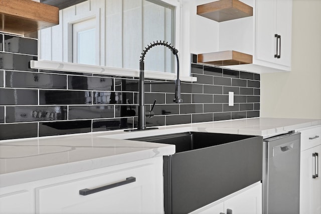 kitchen featuring tasteful backsplash, light stone counters, white cabinetry, and stainless steel dishwasher