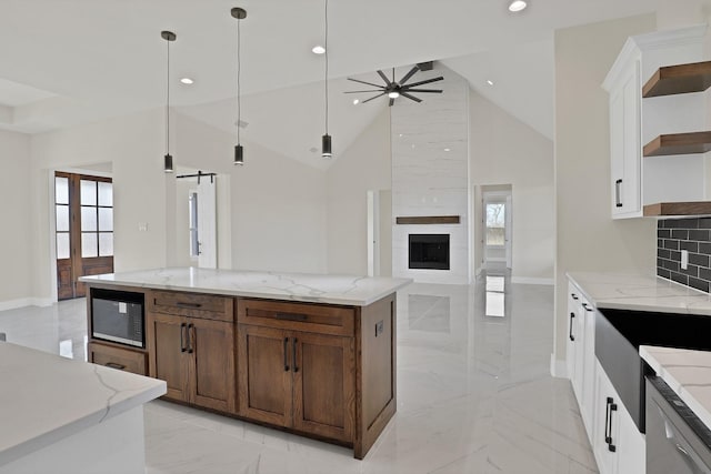 kitchen with built in microwave, white cabinets, backsplash, hanging light fixtures, and ceiling fan