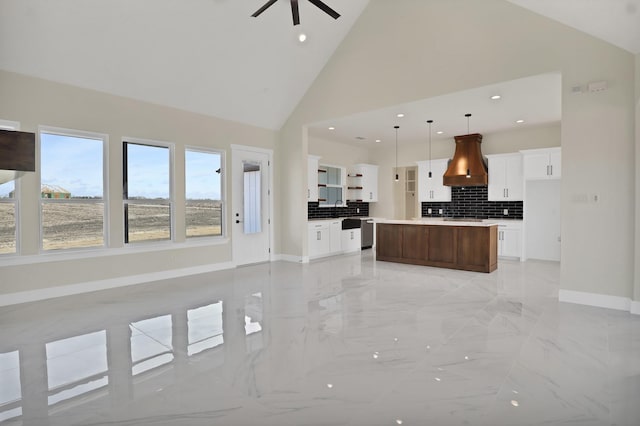 kitchen featuring premium range hood, hanging light fixtures, backsplash, high vaulted ceiling, and a kitchen island