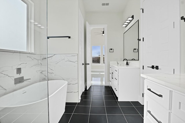 bathroom with a wealth of natural light, a washtub, tile patterned floors, and tile walls