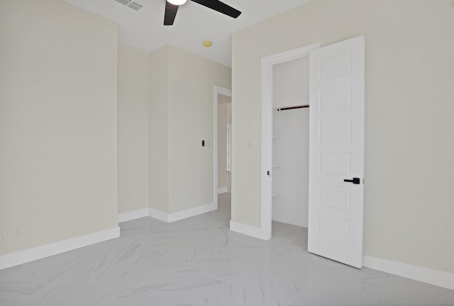 unfurnished bedroom with a walk in closet, ceiling fan, and a closet