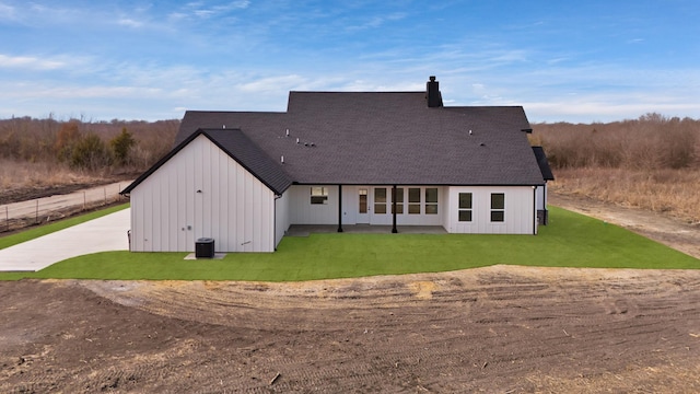 rear view of house featuring central AC and a lawn