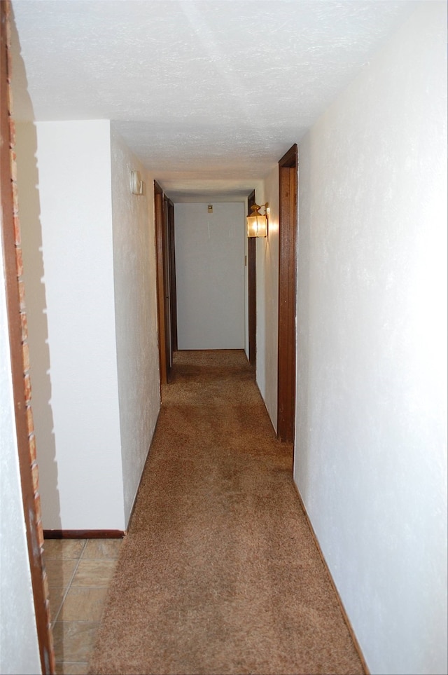 hall with light colored carpet and a textured ceiling