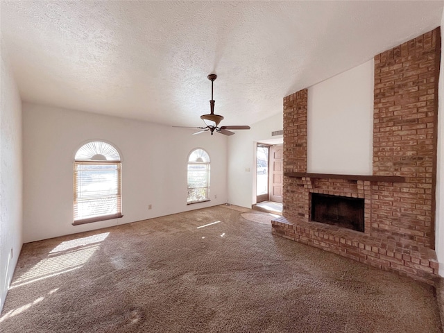 unfurnished living room featuring a brick fireplace, a textured ceiling, ceiling fan, and carpet