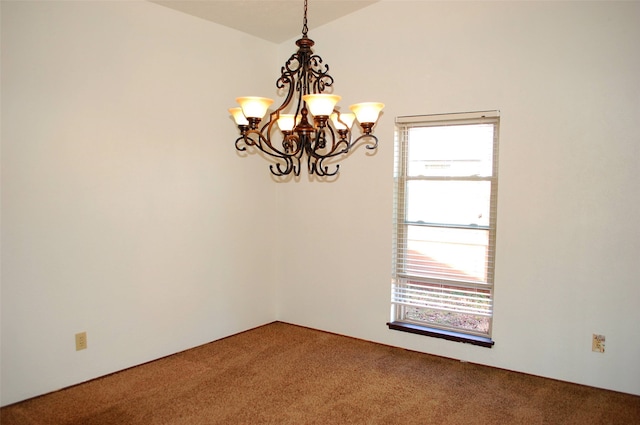 spare room with lofted ceiling, a notable chandelier, and carpet floors