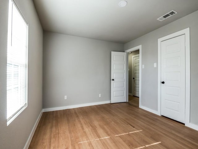 unfurnished bedroom featuring multiple windows and hardwood / wood-style floors