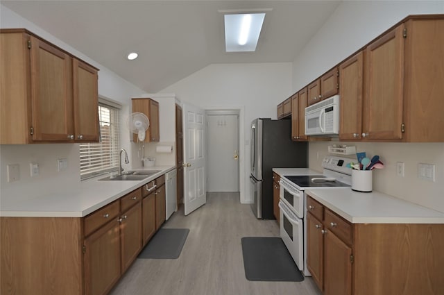 kitchen featuring vaulted ceiling, sink, white appliances, and light hardwood / wood-style flooring