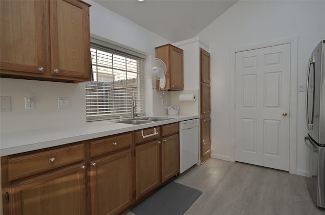 kitchen with vaulted ceiling, stainless steel refrigerator, dishwasher, sink, and light hardwood / wood-style flooring