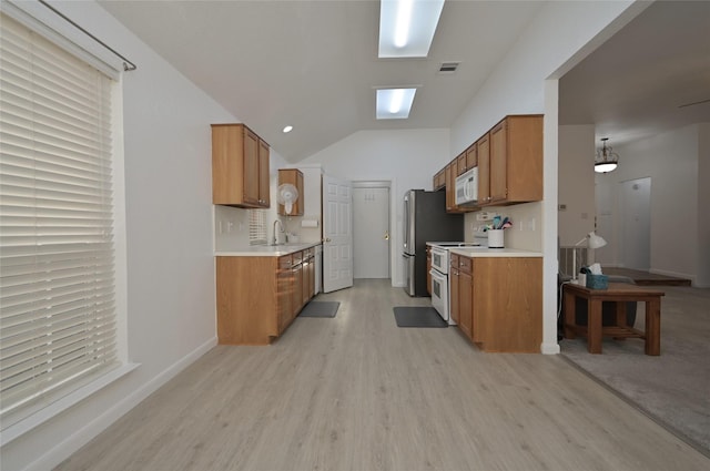 kitchen with lofted ceiling, light wood-type flooring, sink, and white appliances