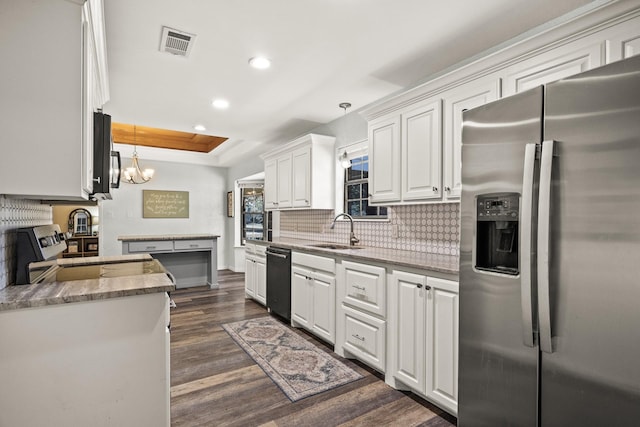 kitchen with appliances with stainless steel finishes, pendant lighting, white cabinets, and dark hardwood / wood-style flooring