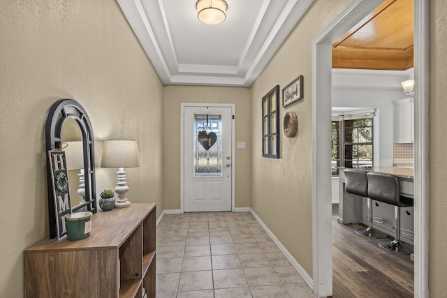 tiled entryway with plenty of natural light and a raised ceiling