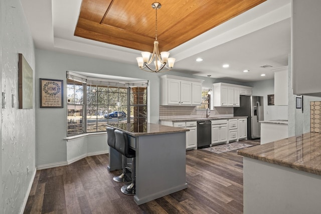 kitchen featuring a raised ceiling, stainless steel fridge, tasteful backsplash, and white cabinets