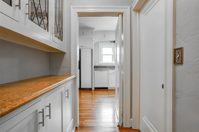 hallway with a textured wall and light wood finished floors