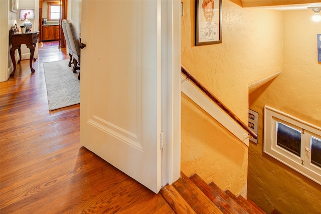 staircase with wood finished floors and a textured wall