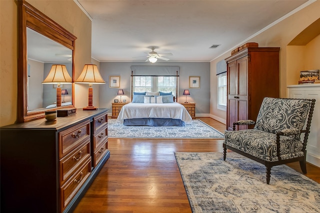 bedroom featuring baseboards, dark wood-type flooring, visible vents, and crown molding