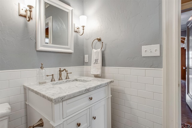 bathroom with wainscoting, vanity, and tile walls