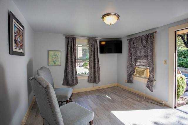 living area featuring baseboards, cooling unit, wood finished floors, and a healthy amount of sunlight