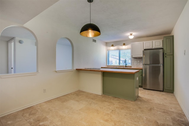 kitchen featuring green cabinetry, white cabinetry, stainless steel refrigerator, and kitchen peninsula