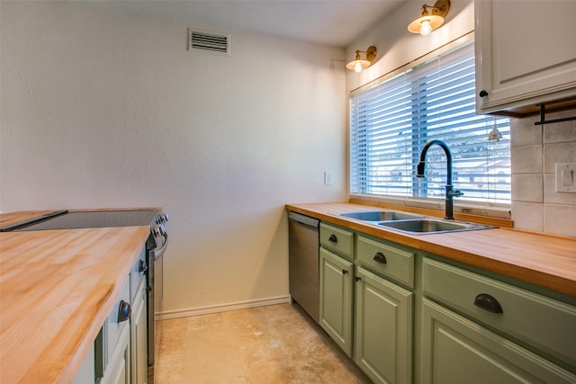 kitchen with butcher block counters, sink, green cabinetry, stainless steel appliances, and decorative backsplash