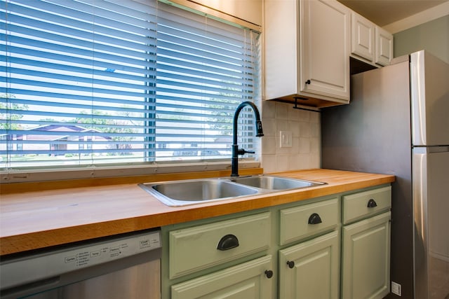 kitchen featuring appliances with stainless steel finishes, wood counters, tasteful backsplash, sink, and white cabinets