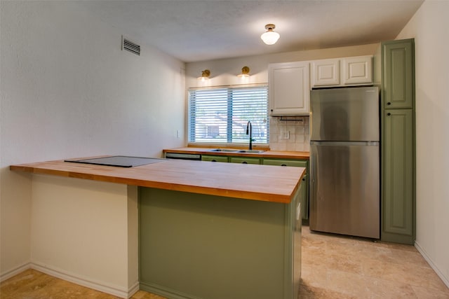 kitchen featuring sink, white cabinets, stainless steel fridge, wooden counters, and decorative backsplash