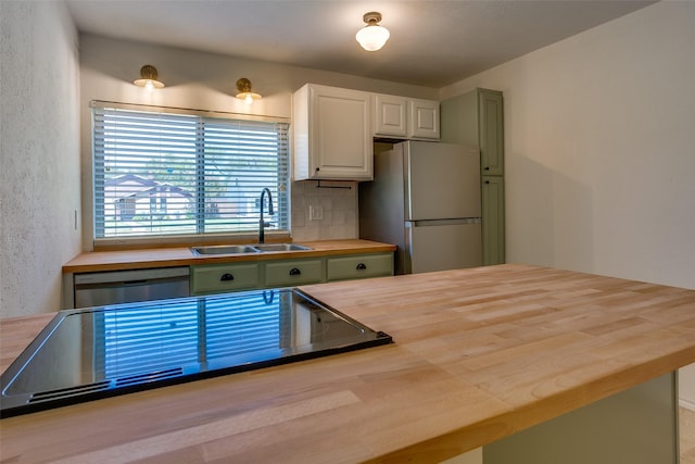 kitchen with sink, fridge, green cabinetry, and dishwasher