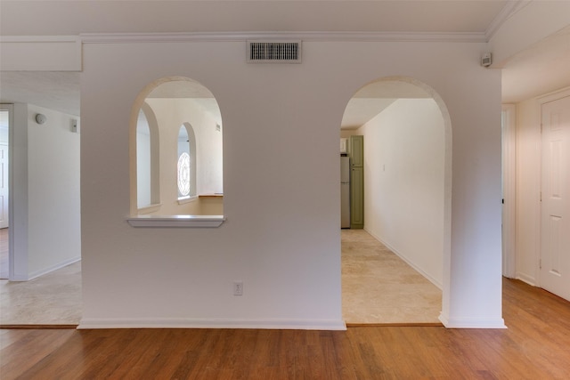 empty room featuring crown molding and light hardwood / wood-style flooring