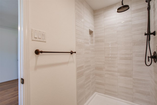 bathroom with hardwood / wood-style flooring and a tile shower