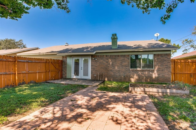 rear view of property with french doors, a patio area, and a lawn