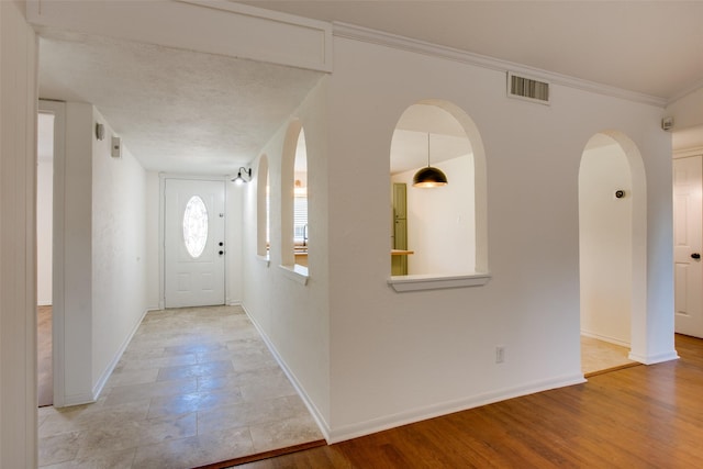 entryway featuring ornamental molding, a textured ceiling, and light hardwood / wood-style flooring