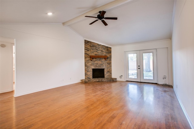 unfurnished living room with french doors, vaulted ceiling with beams, light hardwood / wood-style flooring, a brick fireplace, and ceiling fan