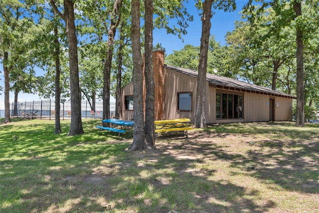 rear view of property featuring a trampoline and a lawn