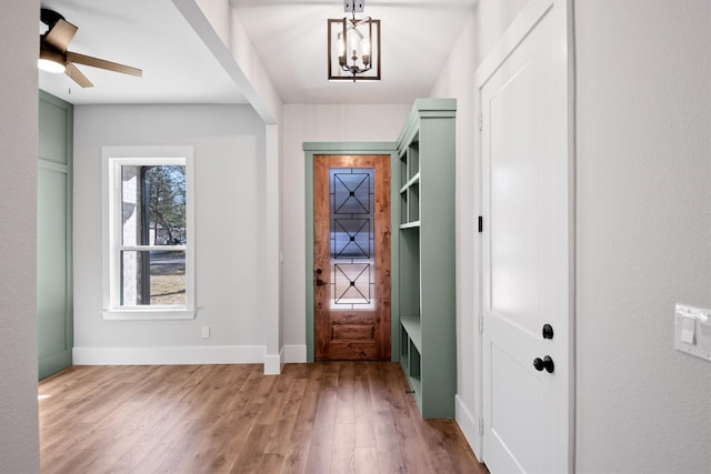 entryway with ceiling fan with notable chandelier and light hardwood / wood-style flooring