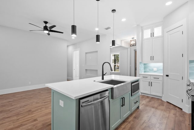 kitchen with pendant lighting, a kitchen island with sink, backsplash, stainless steel appliances, and white cabinets