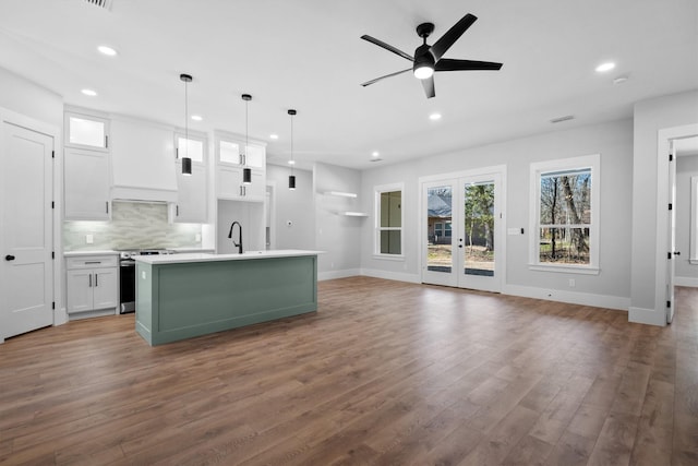 kitchen with stainless steel electric stove, white cabinets, backsplash, and decorative light fixtures