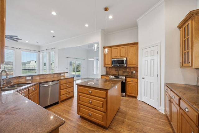 kitchen with sink, hanging light fixtures, stainless steel appliances, tasteful backsplash, and a kitchen island