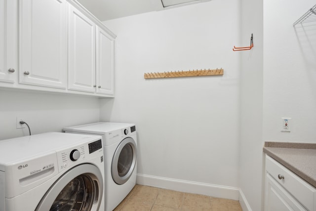 clothes washing area with light tile patterned floors, washing machine and dryer, and cabinets