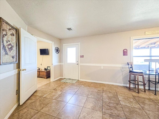 foyer entrance with tile patterned floors, a textured ceiling, and wood walls