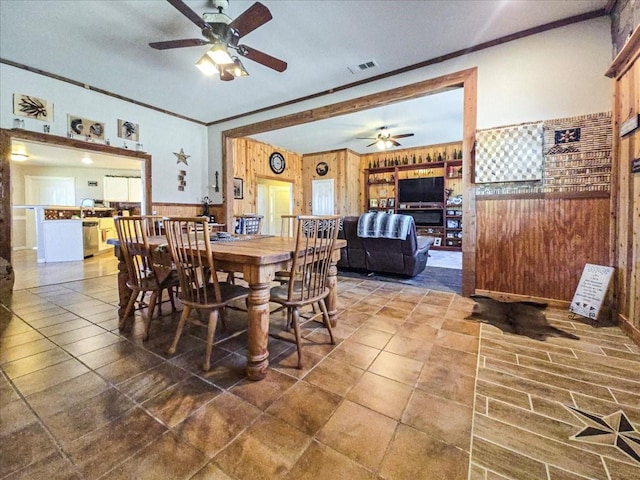 dining space featuring crown molding, ceiling fan, and wooden walls